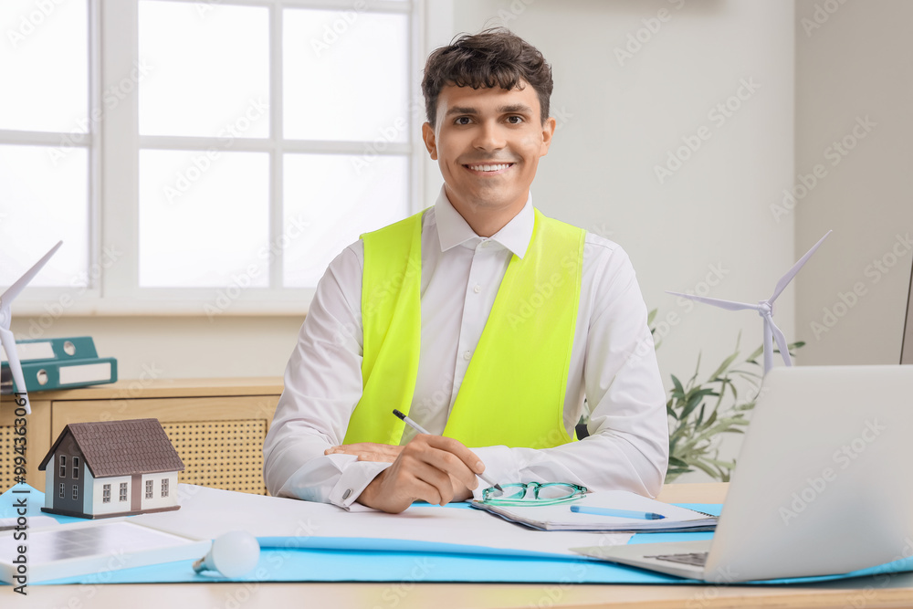 Male engineer with wind turbine model working at table in office Male engineer with wind turbine model working at table in office
