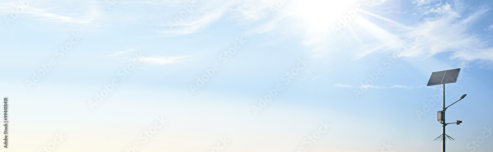 A banner of a solar-powered streetlight against a bright blue sky with the sun shining brightly. A banner of a solar-powered streetlight against a bright blue sky with the sun shining brightly.
