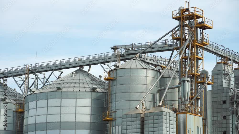 silver silos on agro manufacturing plant for processing drying cleaning and storage of agricultural products, flour, cereals and grain. Large iron barrels of grain. Granary elevator silver silos on agro manufacturing plant for processing drying cleaning and storage of agricultural products, flour, cereals and grain. Large iron barrels of grain. Granary elevator