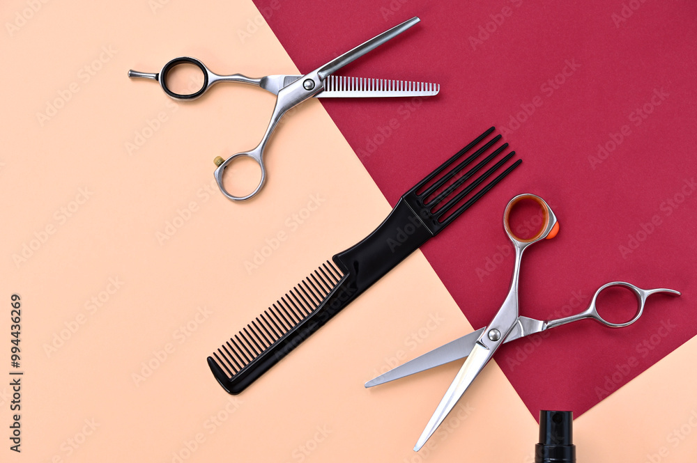 Fototapeta premium professional hairdressing scissors and comb on a pink burgundy background closeup
