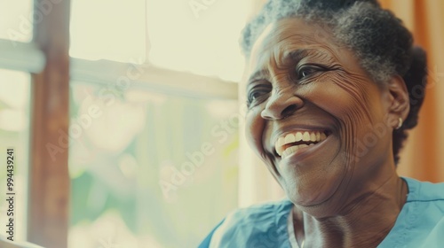 An elderly woman beams with joy, her warm smile radiating happiness as she sits by a bright window. photo