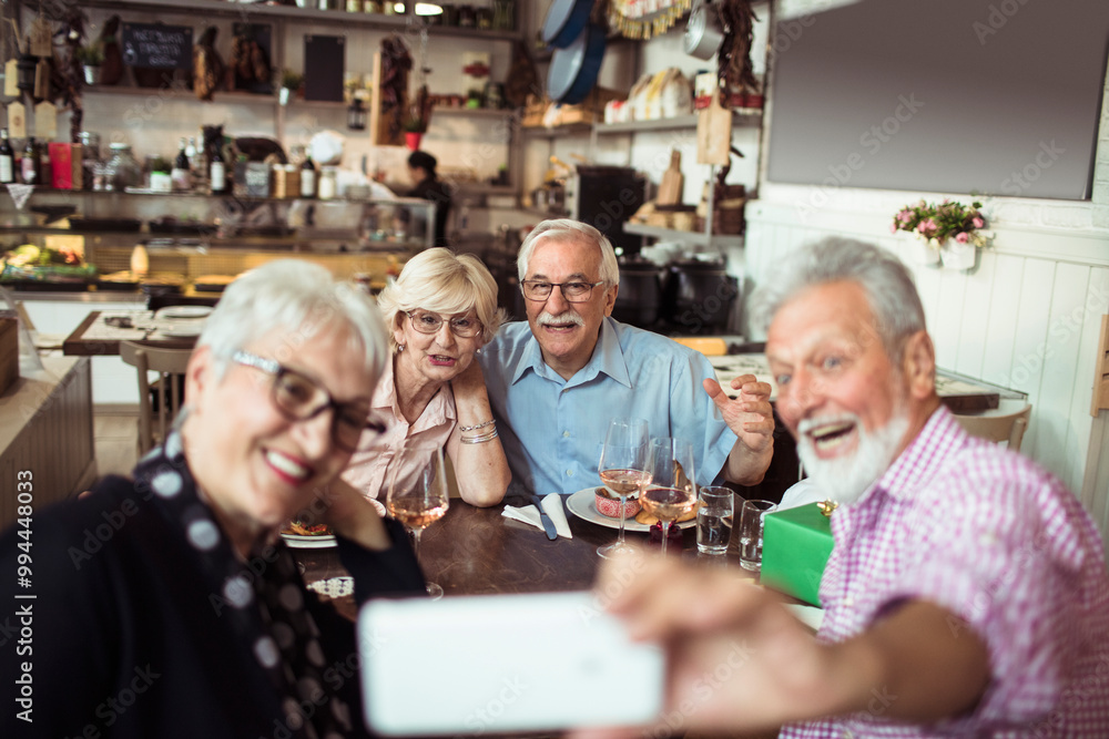 Group of happy senior friends taking selfie together in restaurant Group of happy senior friends taking selfie together in restaurant