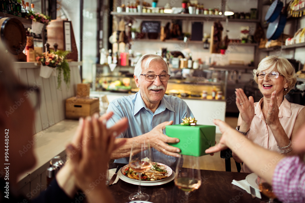 Senior couple celebrating anniversary at restaurant with gifts Senior couple celebrating anniversary at restaurant with gifts