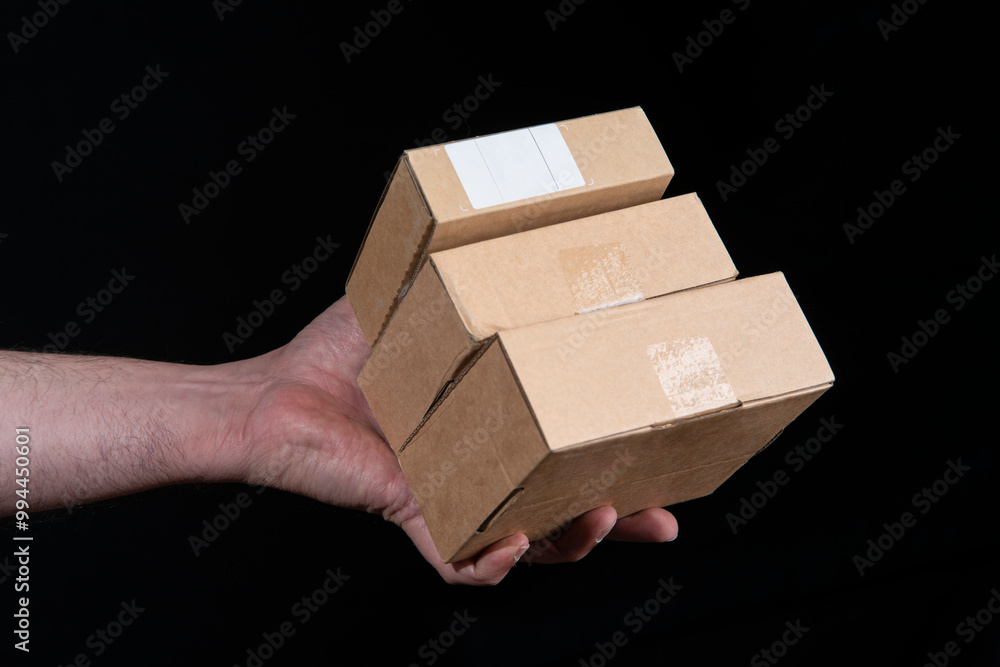 Close-up of man's hand holding three small corrugated cardboard boxes Close-up of man's hand holding three small corrugated cardboard boxes