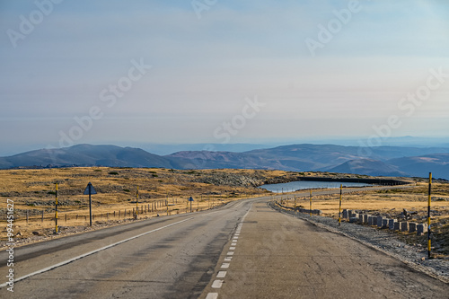 Vista panorâmica da Serra da Estrela, com seus imponentes picos rochosos, vastos campos verdes e céu claro, oferecendo uma paisagem tranquila e natural da maior montanha de Portugal.