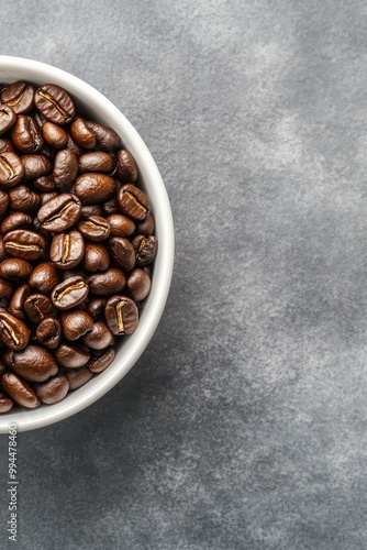 Freshly roasted coffee beans in a white bowl on a gray countertop, perfect fo...