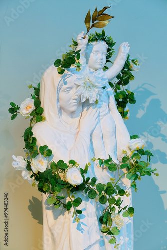 Statue with flowers of Blessed Virgin Mary holding baby Jesus Christ in her arms. . photo