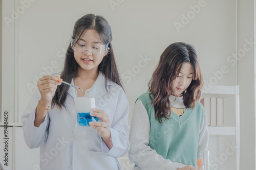 Child kid girl asian young student education two people team group learning and smile have fun happy enjoy with science lab technology with in school classroom has tubetest microscope chemicals table photo