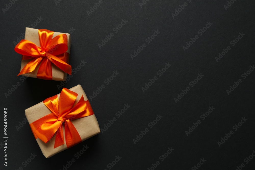 Top view photo of giftboxes with orange satin ribbon bow on black background Top view photo of giftboxes with orange satin ribbon bow on black background