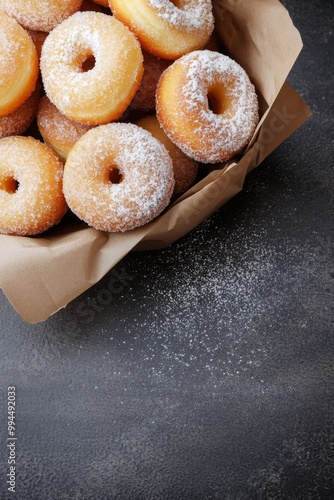 Freshly baked sugary donuts in a rustic brown bag on a dark surface