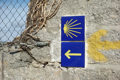 Signpost of the Saint James Way displaying the traditional yellow arrow and scallop