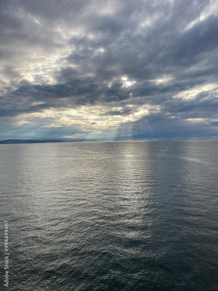 Fototapeta premium Sun rays through the clouds over a calm sea