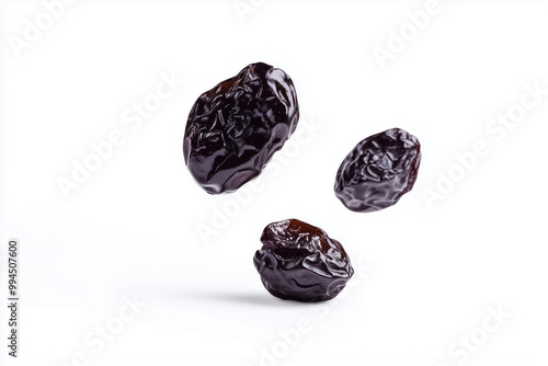 Falling prunes captured in mid-air, showcasing their rich texture against a bright white backdrop photo