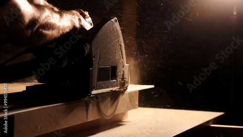 Foto Close-up of a man cuts a wooden plank with an electric circular saw in a workshop