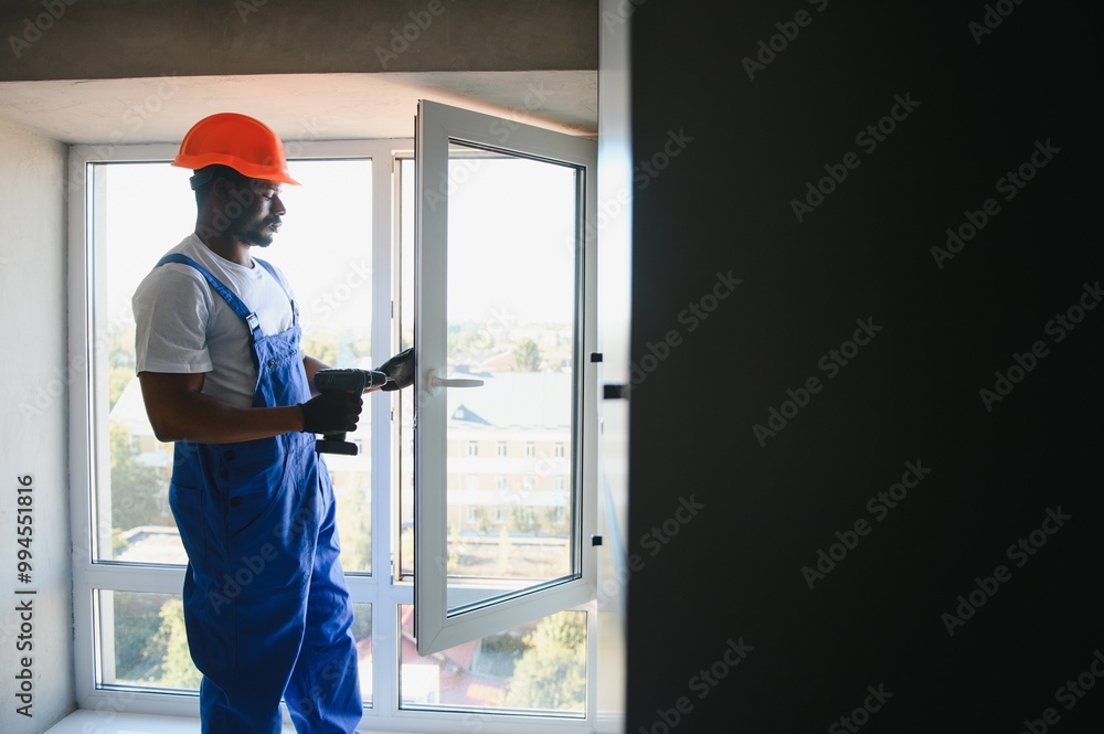 Young African Repairman In Overalls Installing Window Young African Repairman In Overalls Installing Window