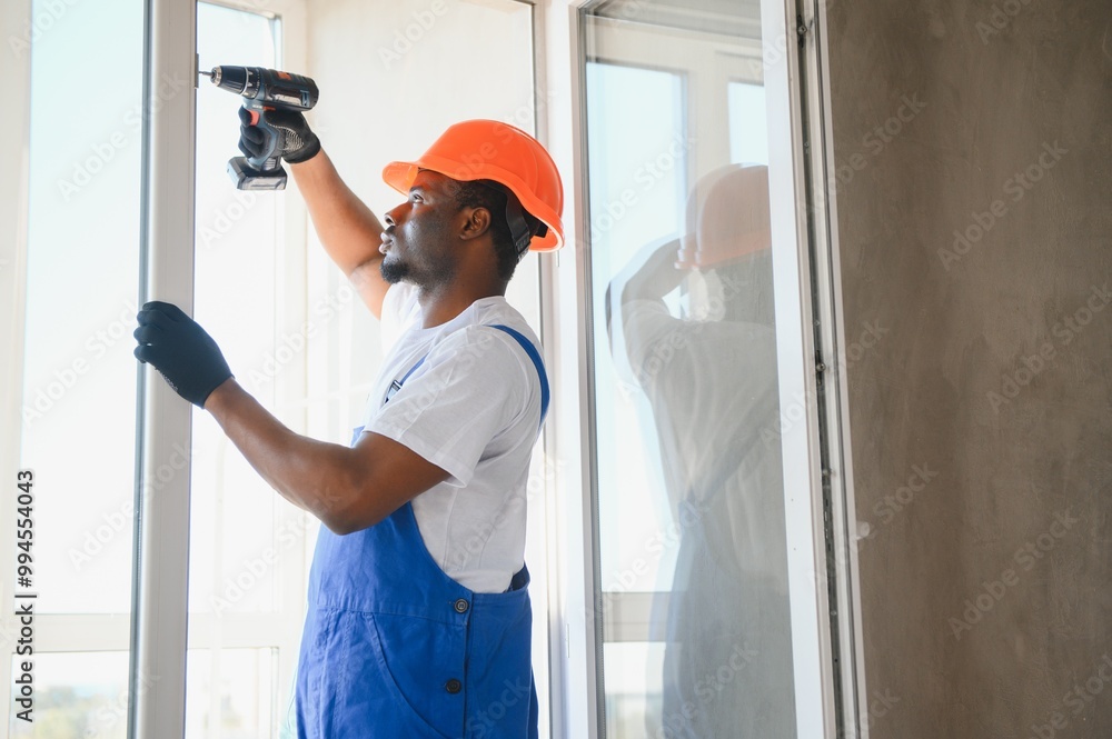 Young African Repairman In Overalls Installing Window Young African Repairman In Overalls Installing Window