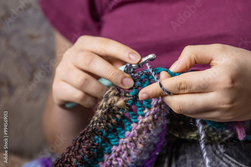 Young womans hands crochet colorful yarn with crocheting hook. Closeup details of handmade needlework art project and creative crafting techniques. Handmade textile artist nitting with yarn. photo