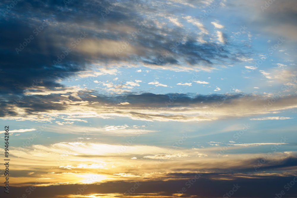 Golden sunlight breaks through layers of dark and light clouds in a vast sky. Golden sunlight breaks through layers of dark and light clouds in a vast sky.