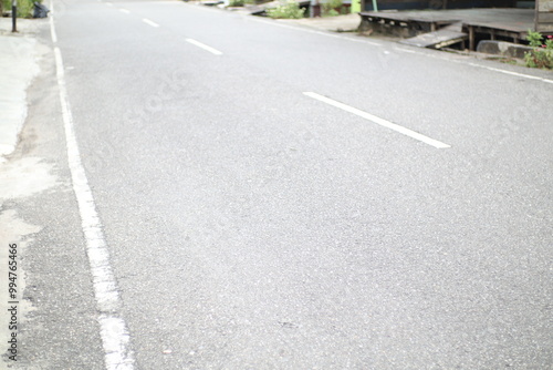 Wallpaper Mural A long, empty asphalt road stretches into the distance. The road is lined with white lines and the sides are slightly unkempt. Torontodigital.ca