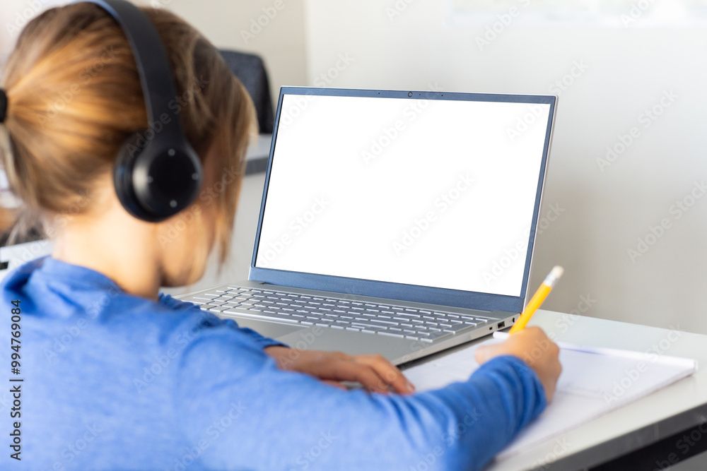 In school, boy wearing headphones writing in notebook while using laptop, copy space In school, boy wearing headphones writing in notebook while using laptop, copy space