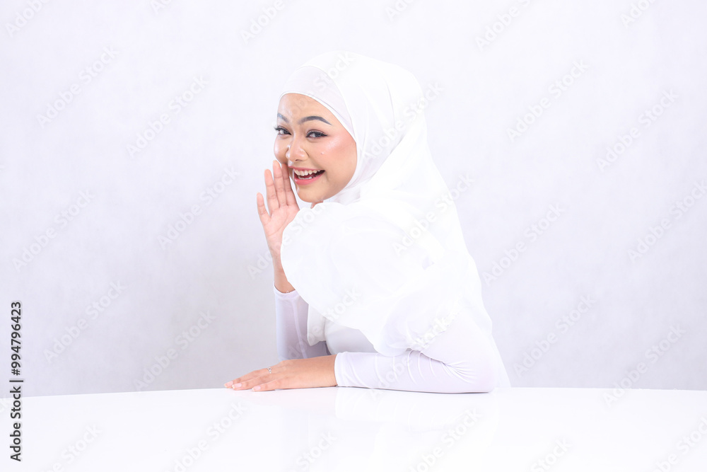 sidewise portrait Beautiful young hijab woman laughing at the camera with her hands leaning on a white table and touching her cheek isolated on a white background. concept of Cosmetology, spa sidewise portrait Beautiful young hijab woman laughing at the camera with her hands leaning on a white table and touching her cheek isolated on a white background. concept of Cosmetology, spa