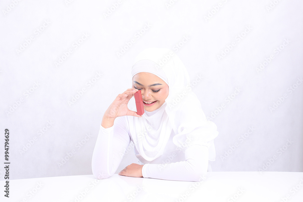 Beautiful veil young woman asia lip makeup view laughing look down hand holding lipstick container and leaning on table isolated white background. beauty education concept, lipstick mock up container Beautiful veil young woman asia lip makeup view laughing look down hand holding lipstick container and leaning on table isolated white background. beauty education concept, lipstick mock up container