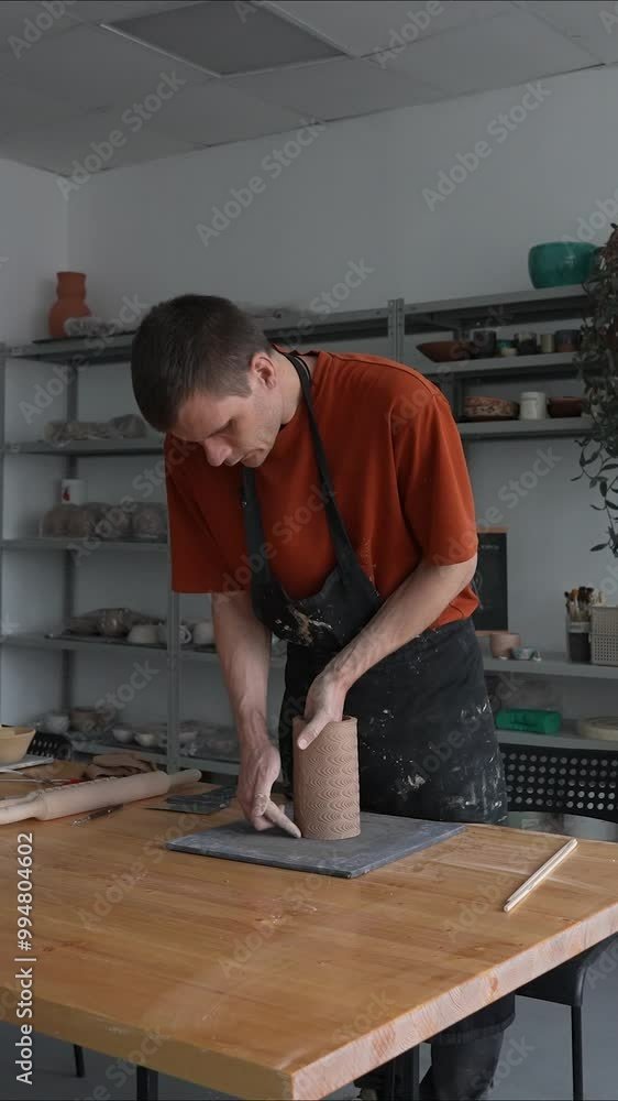 Potter sculpts a patterned cylinder from clay. Vertical video. Potter sculpts a patterned cylinder from clay. Vertical video.