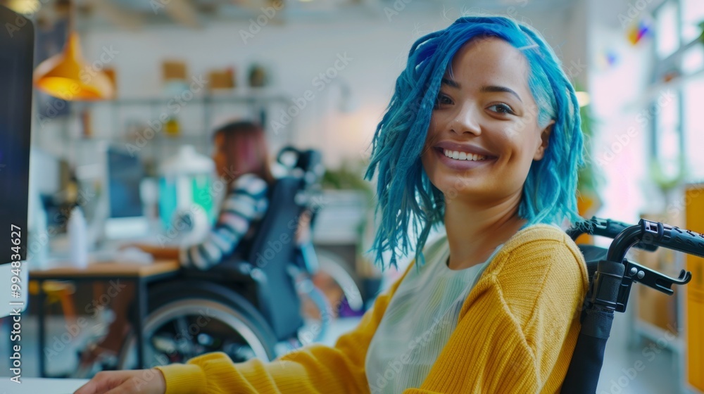 Smiling woman with blue hair in wheelchair working on computer in office. Concept of diversity, inclusion, accessibility and success Smiling woman with blue hair in wheelchair working on computer in office. Concept of diversity, inclusion, accessibility and success