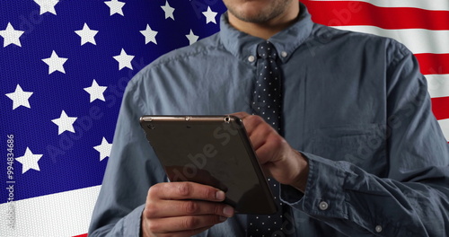 Image of flag of usa over happy caucasian businessman using tablet