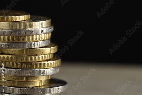 Stack of coins on table against black background, closeup with space for text. Salary concept