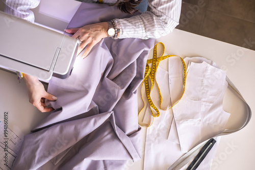 Woman plus size fashion designer uses a sewing machine in her studio. A seamstress sews clothes  photo