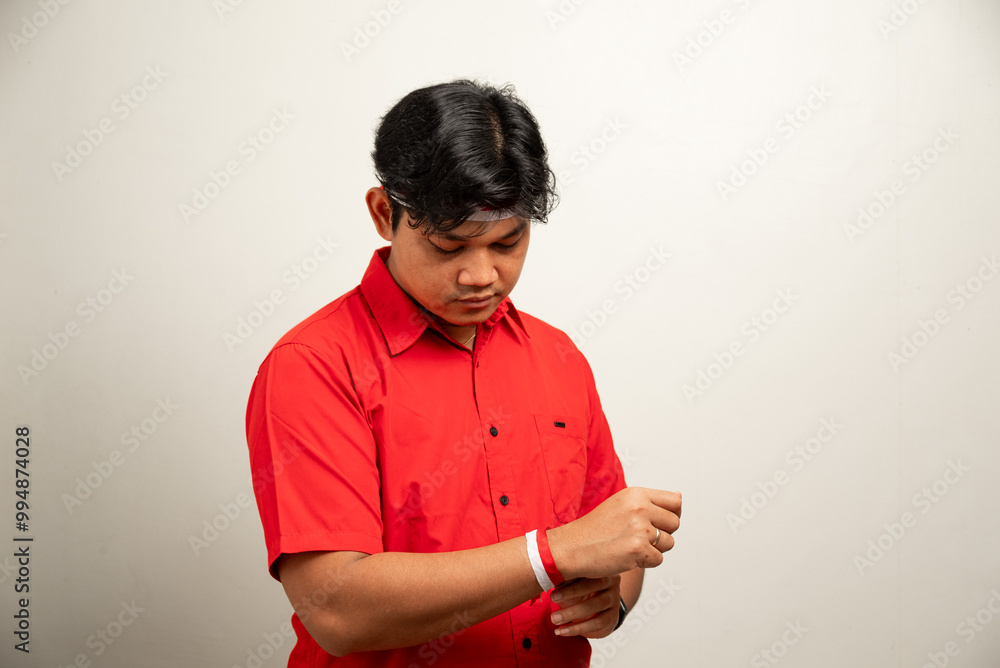 Asian man is tying red and white ribbon to celebrate Indonesia's independence day on August 17 wearing red top and flag headband isolated on white background Asian man is tying red and white ribbon to celebrate Indonesia's independence day on August 17 wearing red top and flag headband isolated on white background