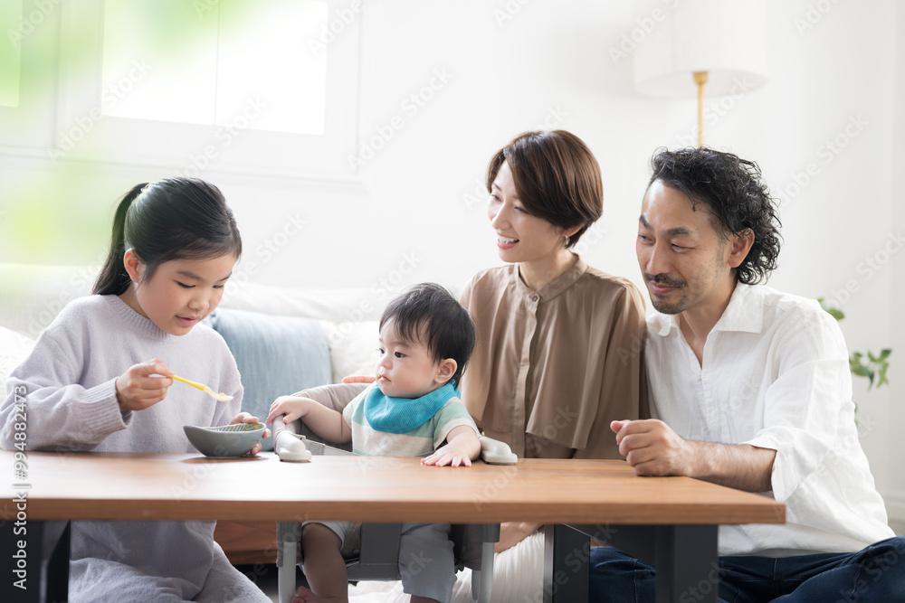 笑顔で赤ちゃんに離乳食をあげる姉と両親 仲良し家族 笑顔で赤ちゃんに離乳食をあげる姉と両親 仲良し家族