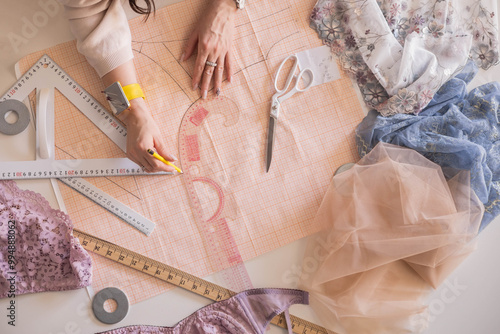 A woman seamstress designs and draws a pattern for underwear on graph paper.  photo