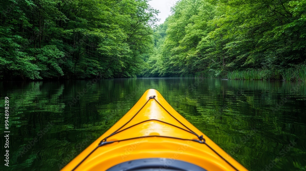 Fototapeta premium A kayak glides through tranquil waters surrounded by lush green trees, inviting adventure and relaxation in nature.