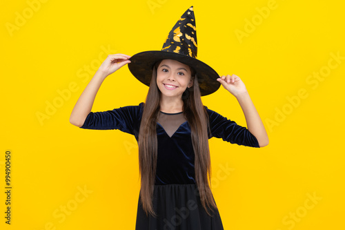 All Hallows. October 31. Teen girl in witch costume. Happy Halloween. Girl witch in Halloween costume isolated on yellow. Trick or treat. Celebrate All Hallows party holiday. Witches and wizards photo