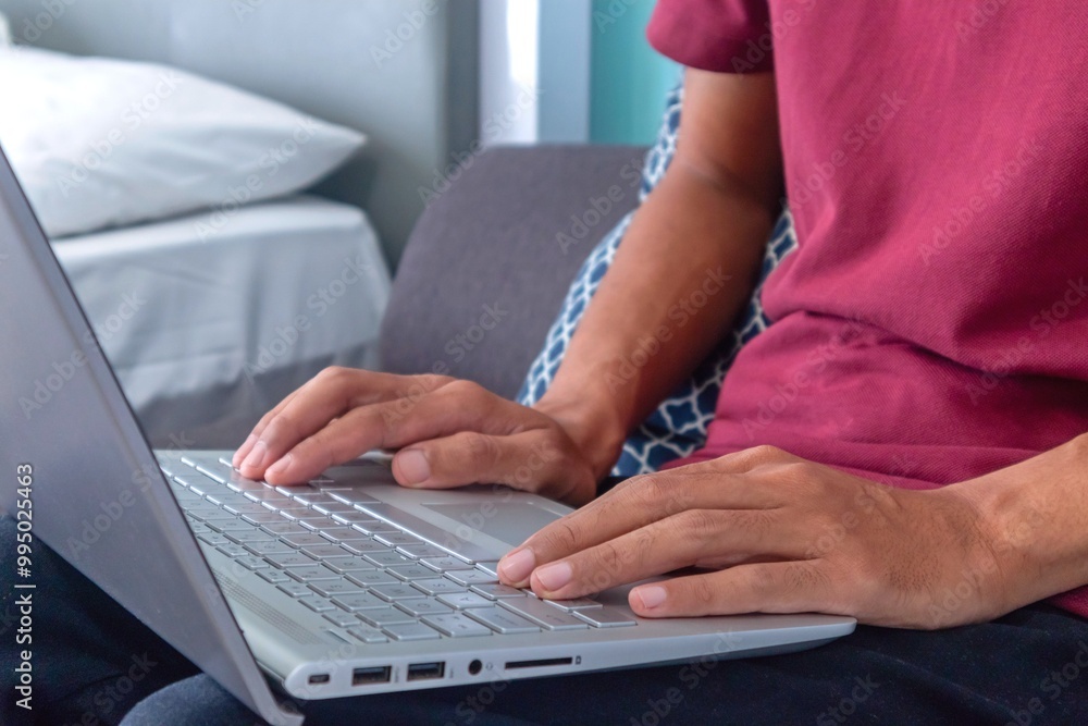 Man working on laptop in his bedroom. Working from home, working on holiday or working from anywhere concept. Man working on laptop in his bedroom. Working from home, working on holiday or working from anywhere concept.