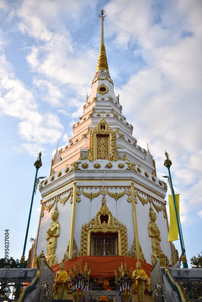 Fototapeta premium A stunning pagoda adorned with intricate golden details, rising against a backdrop of fluffy clouds, capturing the essence of traditional architecture.