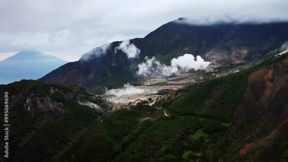 Aerial video of Mount Papandayan's volcanic crater, encircled by lush mountains under a sky with drifting clouds, capturing the dramatic and stunning beauty of this natural landscape in Indonesia. Aerial video of Mount Papandayan's volcanic crater, encircled by lush mountains under a sky with drifting clouds, capturing the dramatic and stunning beauty of this natural landscape in Indonesia.