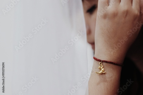 a woman wearing a gold bracelet and holding her hand to her face