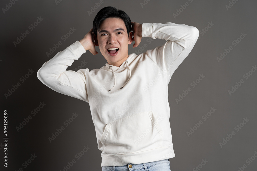 Portrait of Asian man wearing hoodie and posing on gray background. Portrait of Asian man wearing hoodie and posing on gray background.