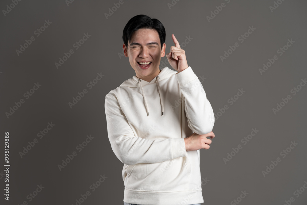 Portrait of Asian man wearing hoodie and posing on gray background. Portrait of Asian man wearing hoodie and posing on gray background.