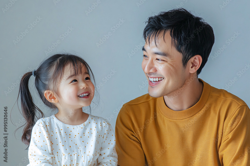 Young Chinese father and cute daughter interacting and smiling in plain background, dressed in simple Uniqlo clothes, family photo portrait. Young Chinese father and cute daughter interacting and smiling in plain background, dressed in simple Uniqlo clothes, family photo portrait.