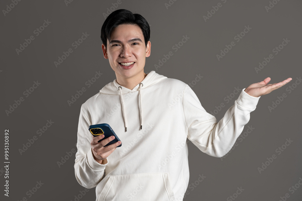 Portrait of Asian man wearing hoodie and posing on gray background. Portrait of Asian man wearing hoodie and posing on gray background.