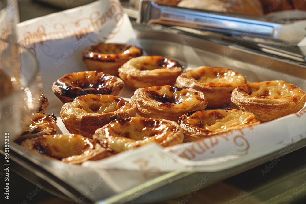 Fresh baked Pastel de nata or Pastel de belém .The most famous sweet in Portugal. Tart on baking sheet/ Fresh baked Pastel de nata or Pastel de belém .The most famous sweet in Portugal. Tart on baking sheet/