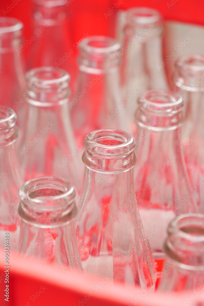 Empty glass bottles arranged in a vibrant red basket for storage and organization Empty glass bottles arranged in a vibrant red basket for storage and organization