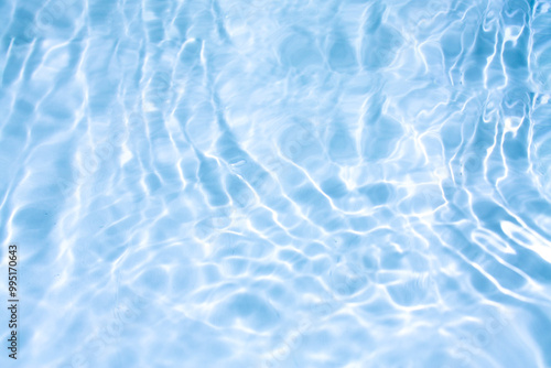 Blue water with ripples on the surface. Defocus blurred transparent blue colored clear calm water surface texture with splashes and bubbles. Water waves with shining pattern texture background.