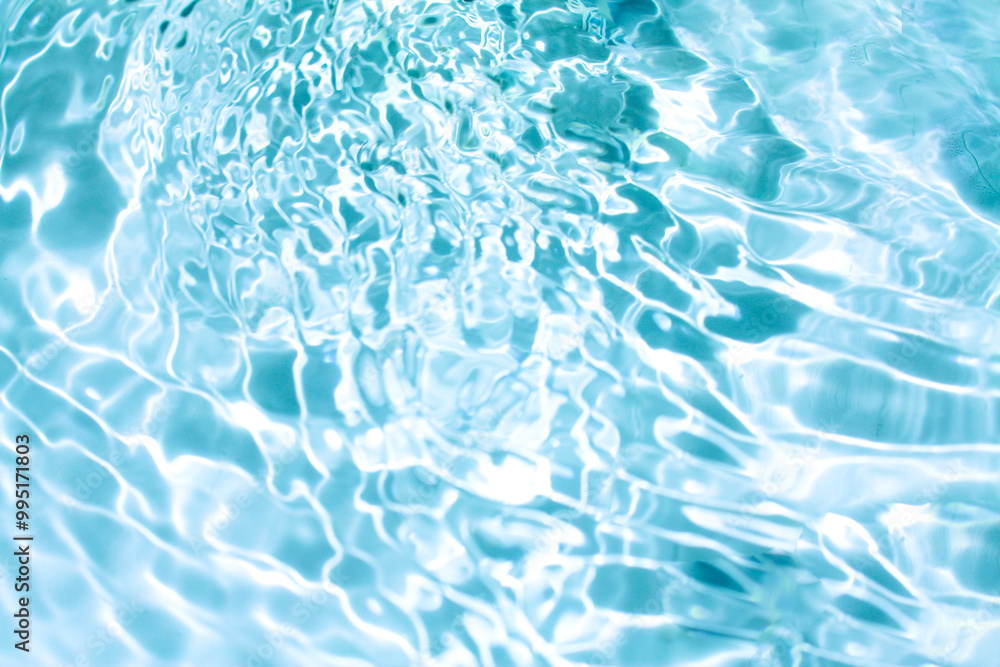 Obraz premium Blue water with ripples on the surface. Defocus blurred transparent blue colored clear calm water surface texture with splashes and bubbles. Water waves with shining pattern texture background.