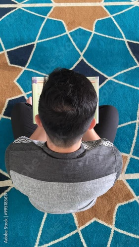 Top view of a Muslim man reading the Quran in a mosque