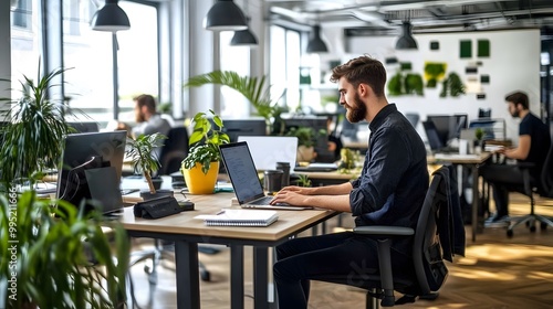 A modern office space featuring individuals working at desks surrounded by plants in a bright, open environment.